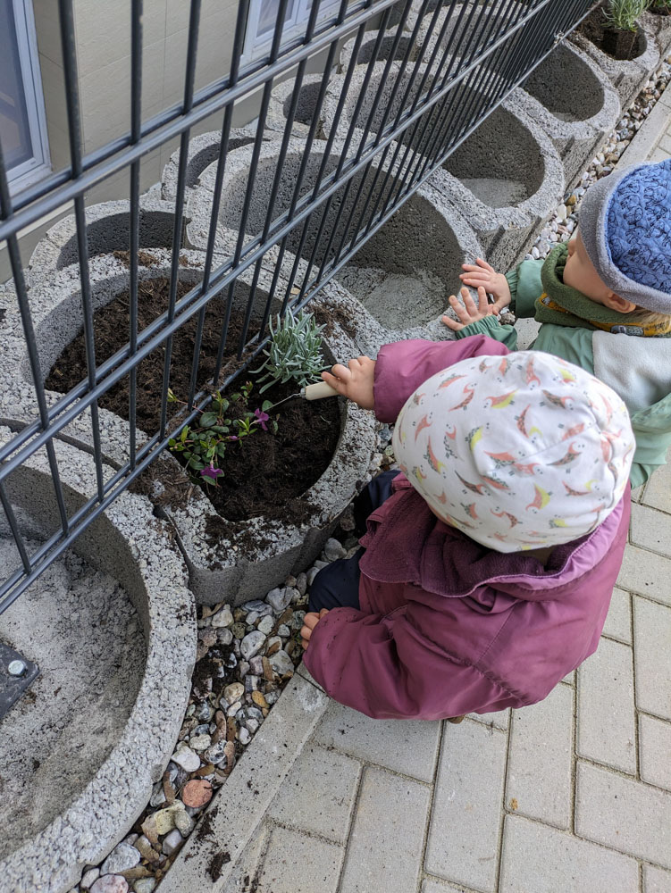 Ein kleines Mädchen pflanzt etwas in ein rundes Beet