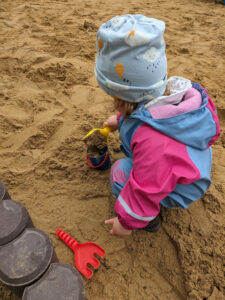 Ein kleines Mädchen spielt in einem Sandkasten